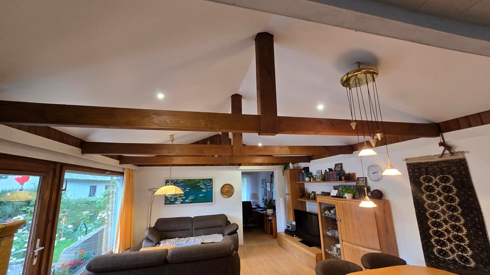 Nachher: weiße Spanndecke mit LED-Spots zwischen den Holzbalken