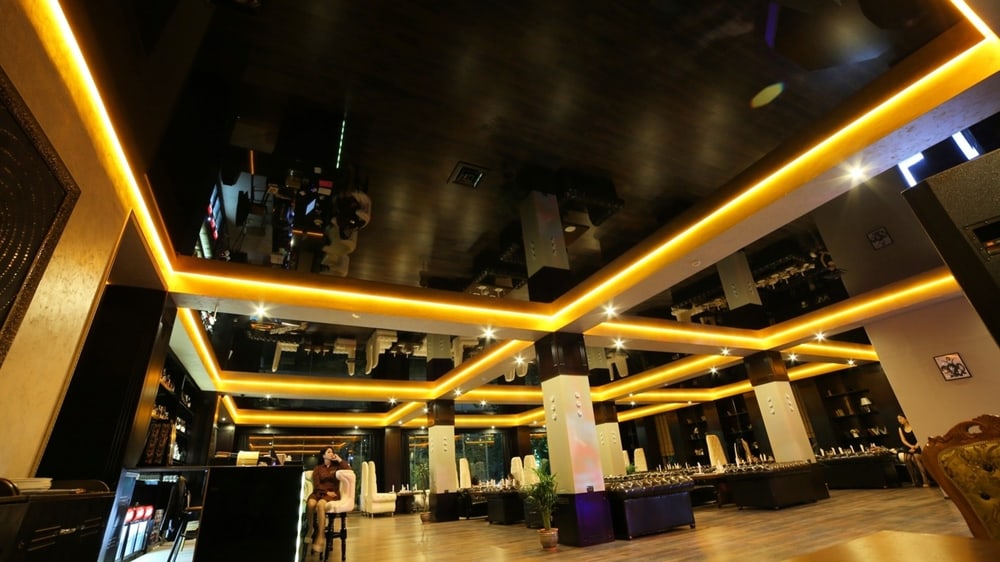 Schwarze Hochglanz-Spanndecke mit goldenen LED-Lichtlinien in einem Veranstaltungsraum